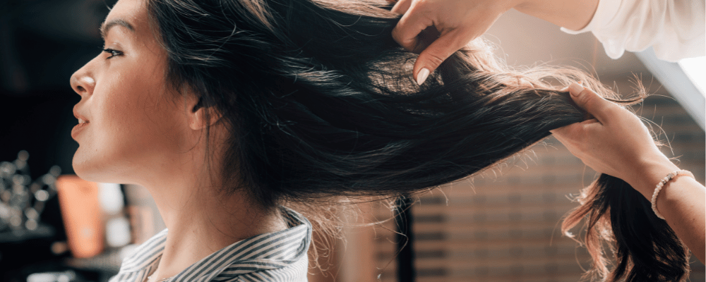 Stylist preparing a client’s long dark hair for a hair-up style at re:new in Woodhall Spa
