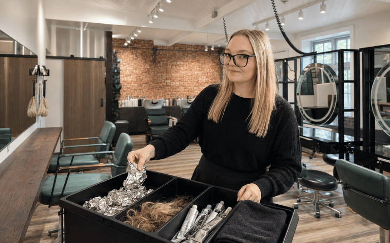 Emily sorting hair, foil and colour tubes for salon recycling at re:new Hair & Beauty