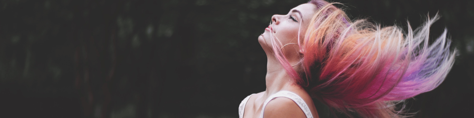 Woman showing vibrant pink, red and purple coloured hair in motion